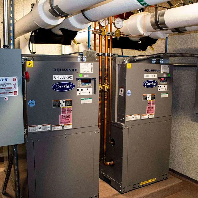 A training facility room with two large heaters and visible pipes in a Chicago, IL