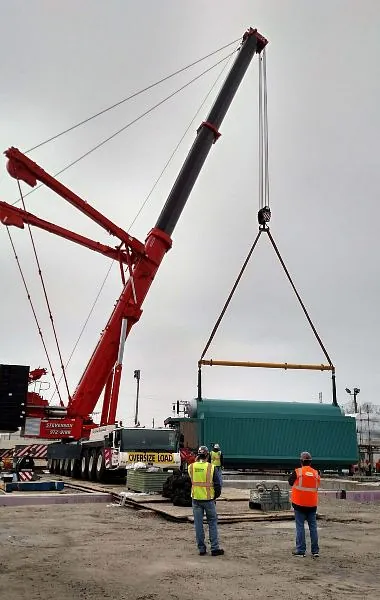 A crane is lifting a large container onto a truck for transport in Chicago, IL