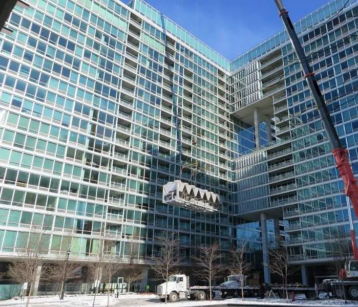 A crane is lifting a large block in snowy weather in Chicago, IL